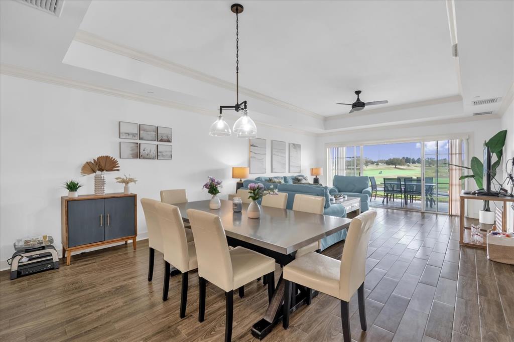 A dining area with a metal table and chairs opens to a living room and patio — 1362 CENTRE COURT RIDGE DRIVE UNIT 102, REUNION, FL