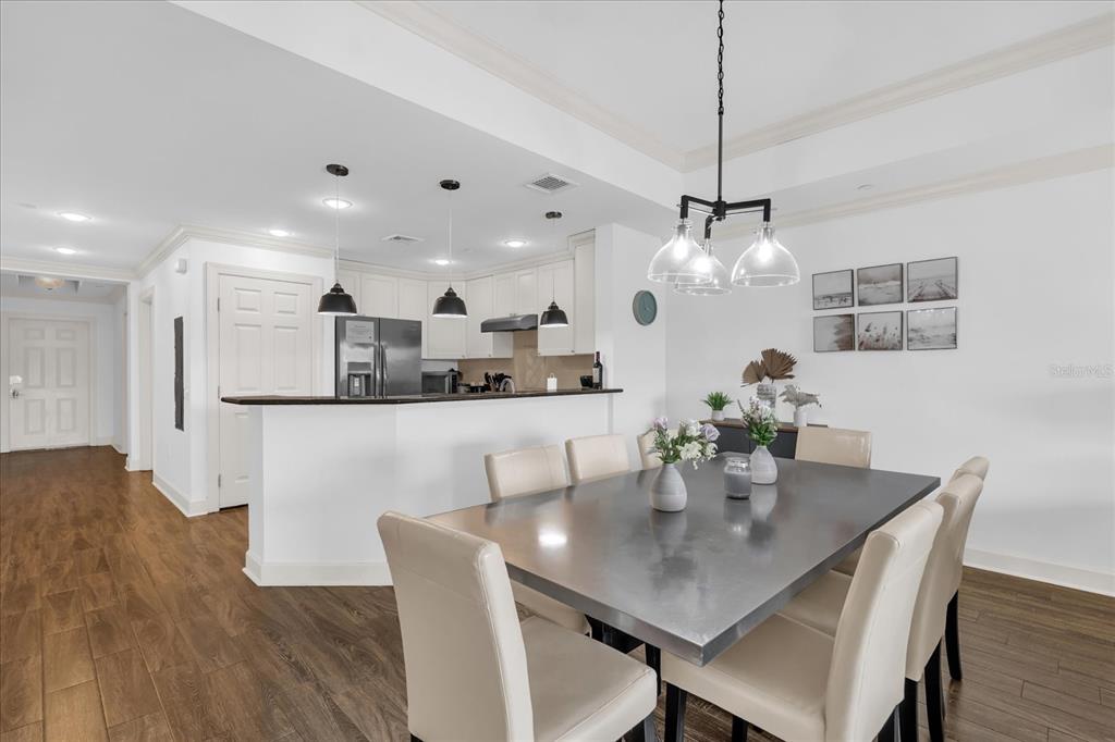 A dining area with a metal table and chairs sits adjacent to an open kitchen — 1362 CENTRE COURT RIDGE DRIVE UNIT 102, REUNION, FL