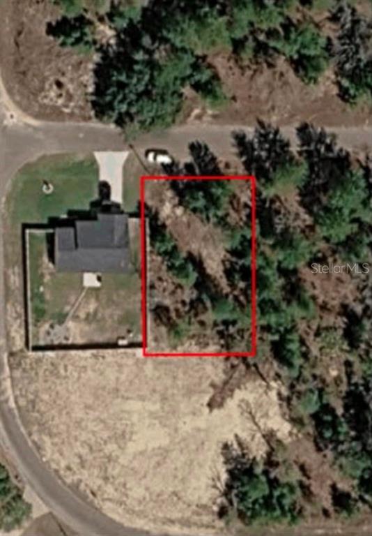 An aerial view shows a rectangular vacant lot outlined in red next to a house — 22 FISHER RUN LANE, OCKLAWAHA, FL