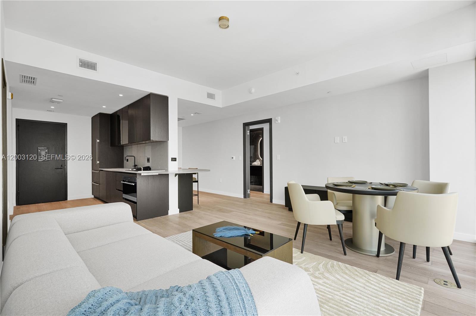 An open-concept living and dining area features a modern kitchen with dark cabinetry — 20 NE 11th St # 4006, Miami FL 33132, MIAMI, FL