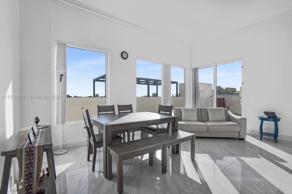 A bright, open-concept living and dining area features white walls, tile flooring, and large windows — 10 SW South River Dr # 608, Miami FL 33130, MIAMI, FL