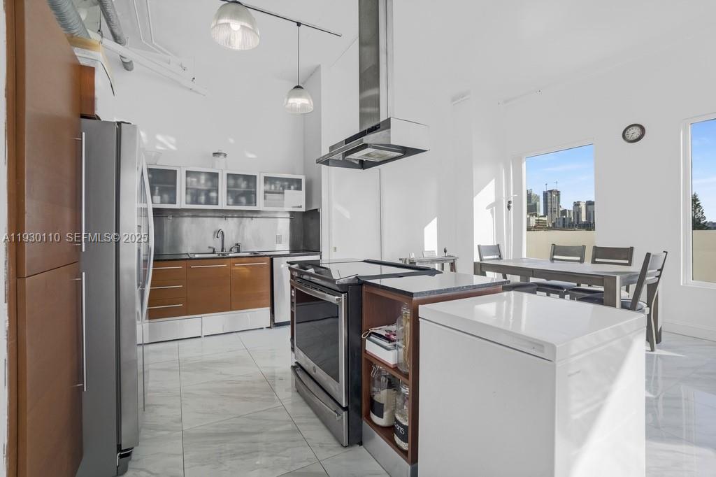 A modern kitchen features white cabinets, wood-toned lower drawers, stainless steel appliances, and tile flooring — 10 SW South River Dr # 608, Miami FL 33130, MIAMI, FL