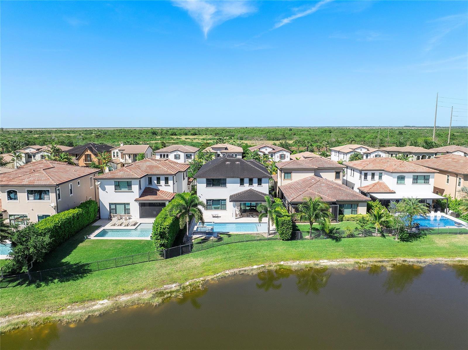 An aerial view shows several suburban houses with swimming pools bordering a small lake — 11036 Meridian Drive N, Parkland FL 33076, PARKLAND, FL