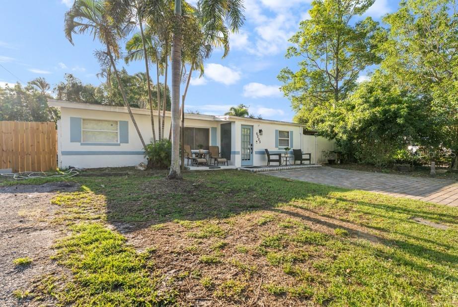 A single-story house with a light-colored exterior, a paved patio, and palm trees — 6205 65TH STREET N, PINELLAS PARK, FL