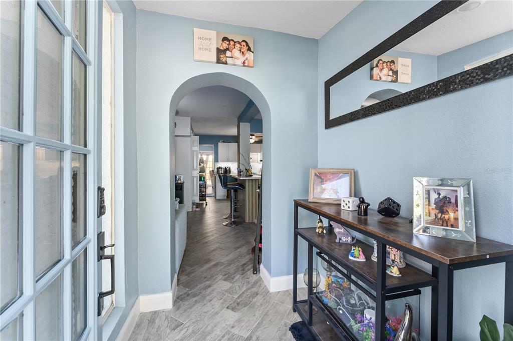 An entryway with light blue walls, gray wood-look tile flooring, and an arched doorway — 6205 65TH STREET N, PINELLAS PARK, FL