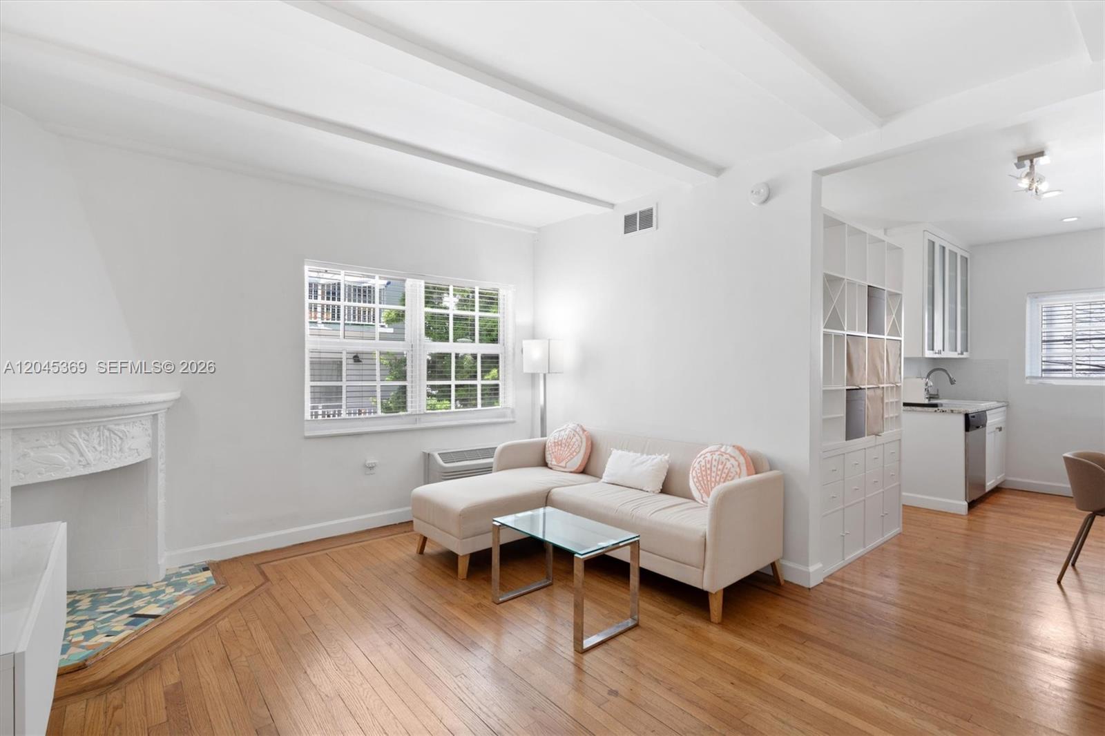 A living room with hardwood floors, a fireplace, a sectional sofa, and an adjacent kitchen — 439 15th St # 8, Miami Beach FL 33139, MIAMI BEACH, FL