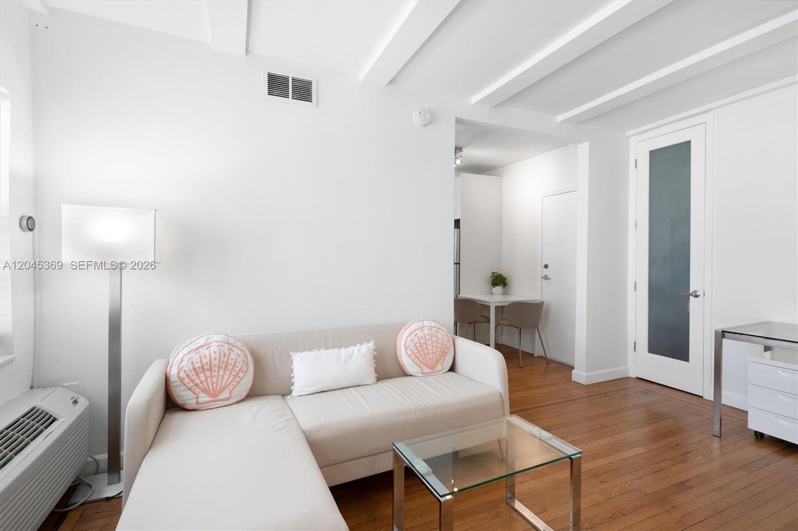 A living room features a beige sectional sofa, a glass coffee table, and hardwood floors — 439 15th St # 8, Miami Beach FL 33139, MIAMI BEACH, FL