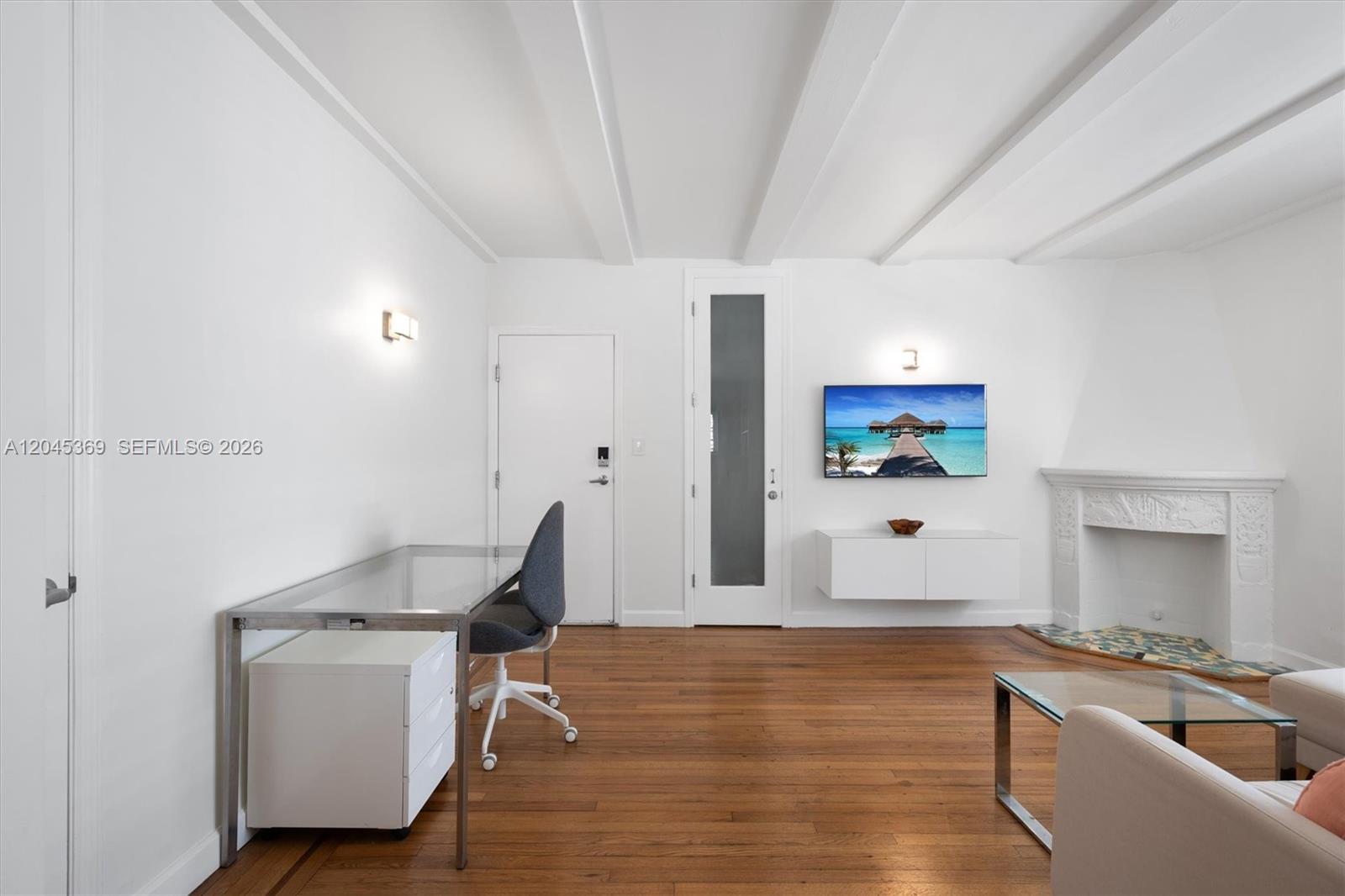 A bright room features a glass desk, a wall-mounted television, and a white fireplace — 439 15th St # 8, Miami Beach FL 33139, MIAMI BEACH, FL