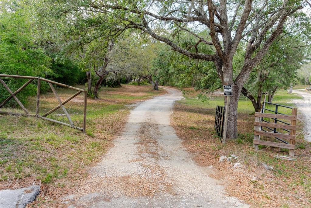 A dirt driveway leads through a wooded area past a wooden fence and gate — 12531 LITTLE PETE COURT, HUDSON, FL