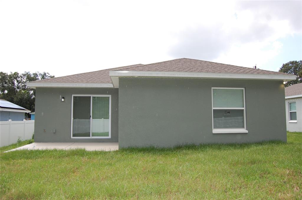 The back exterior of a gray house features a sliding glass door and one window — 319 DIXIE HIGHWAY, AUBURNDALE, FL