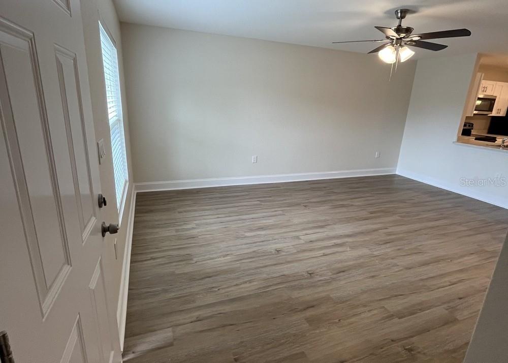An empty room with light wood-look flooring, a ceiling fan, and a view into a kitchen — 319 DIXIE HIGHWAY, AUBURNDALE, FL