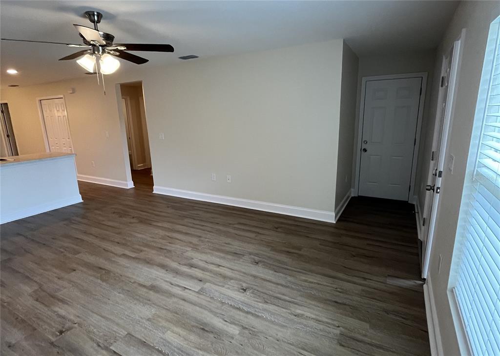 A living room features wood-look flooring, a ceiling fan, and a white entry door — 319 DIXIE HIGHWAY, AUBURNDALE, FL