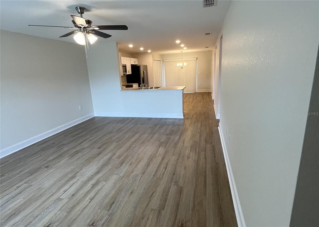 An open-concept living area features wood-look flooring, a ceiling fan, and an adjacent kitchen — 319 DIXIE HIGHWAY, AUBURNDALE, FL