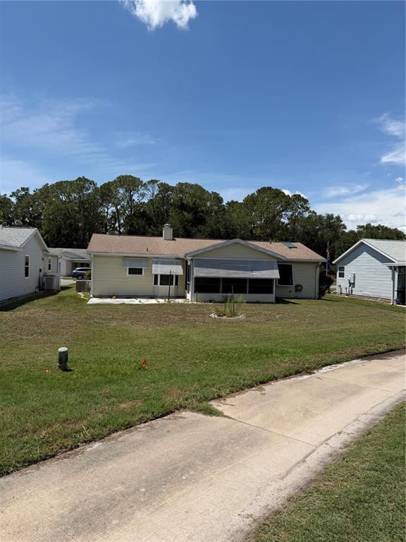 A single-story house with light siding, a screened-in porch, and a concrete driveway — 412 WESTWOOD DRIVE, LEESBURG, FL