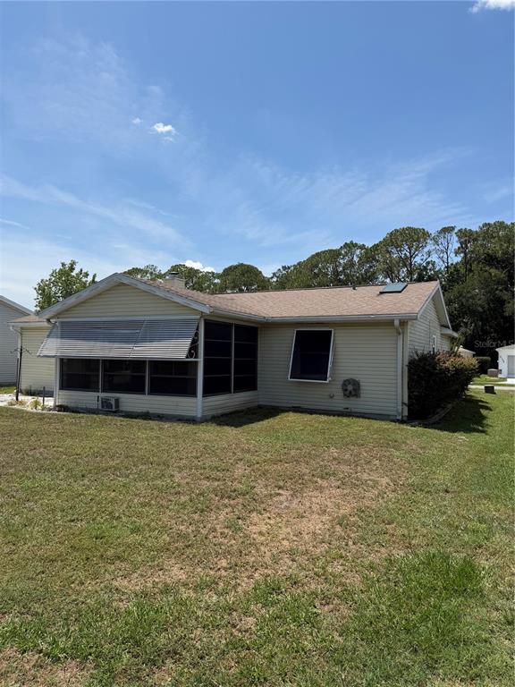 The exterior of a light-colored, single-story house features a screened-in porch and a grassy yard — 412 WESTWOOD DRIVE, LEESBURG, FL
