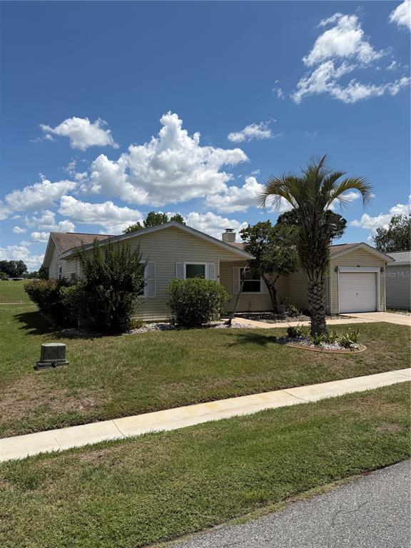 A single-story house with light yellow siding, a one-car garage, and a palm tree — 412 WESTWOOD DRIVE, LEESBURG, FL