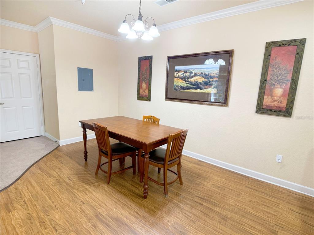 A dining room features wood-look flooring, a wooden table with three chairs, and wall art — 8010 TUSCANY WAY UNIT 3103, DAVENPORT, FL