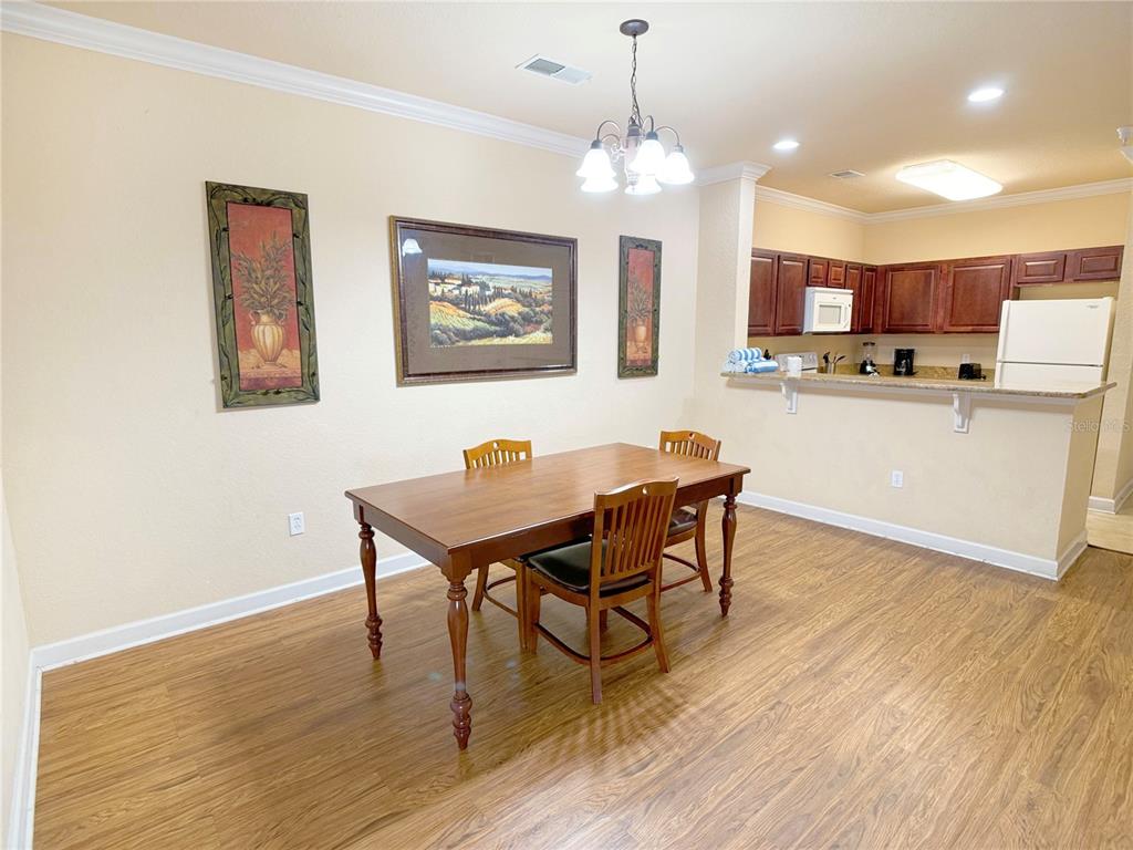 A dining area with a wooden table and chairs sits adjacent to an open kitchen — 8010 TUSCANY WAY UNIT 3103, DAVENPORT, FL