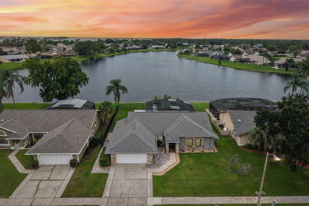 An aerial view shows a suburban house with a pool cage overlooking a lake — 14636 EAGLES CROSSING DRIVE, ORLANDO, FL