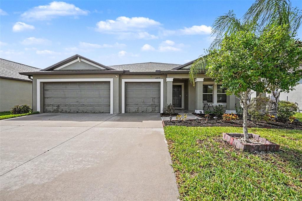 A single-story house with a three-car garage, a concrete driveway, and a front lawn — 10829 CRUSHED GRAPE DRIVE, RIVERVIEW, FL