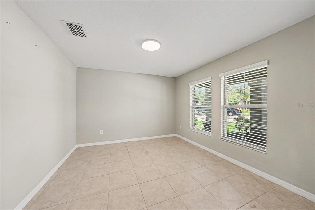 An empty room features light-colored walls, tile flooring, a ceiling light, and two windows — 10829 CRUSHED GRAPE DRIVE, RIVERVIEW, FL