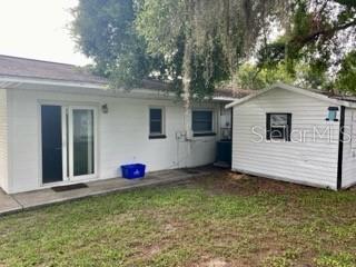 The exterior of a white house features a sliding glass door and an adjacent shed — 4808 20TH STREET, ZEPHYRHILLS, FL
