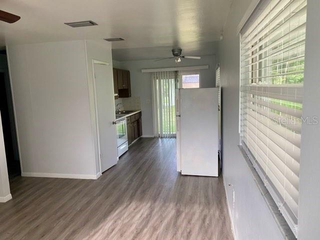 A kitchen and dining area with light wood-look flooring, white walls, and a white refrigerator — 4808 20TH STREET, ZEPHYRHILLS, FL