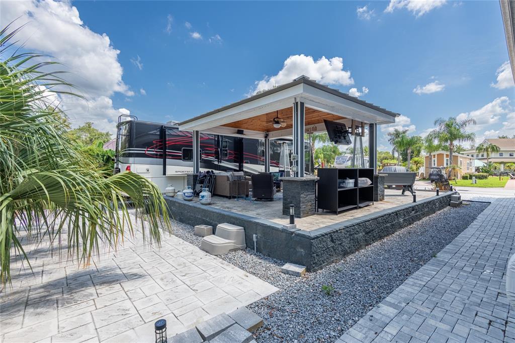 An outdoor patio features a covered pavilion with a television, seating, and stone masonry — 6757 AMANDA VISTA CIRCLE, LAND O LAKES, FL