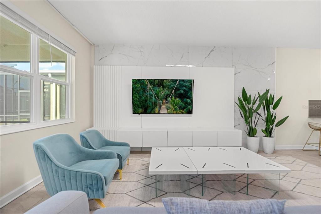 A living room features a white media wall, a patterned rug, and two blue chairs — 4548 TARGET BOULEVARD, KISSIMMEE, FL