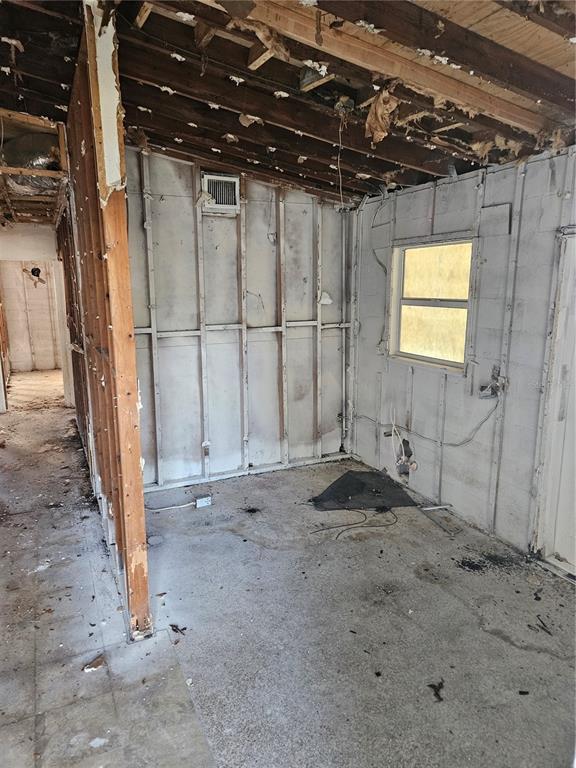 An unfinished room with exposed wall studs, open ceiling joists, and a single window — 2814 PALMADELIA AVENUE, SARASOTA, FL