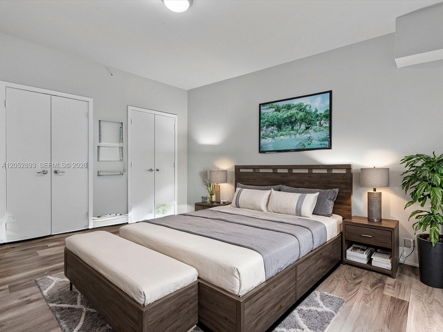 A bedroom features a wooden platform bed, matching nightstands, a bench, and two closet doors — 888 Biscayne Blvd # 509, Miami FL 33132, MIAMI, FL