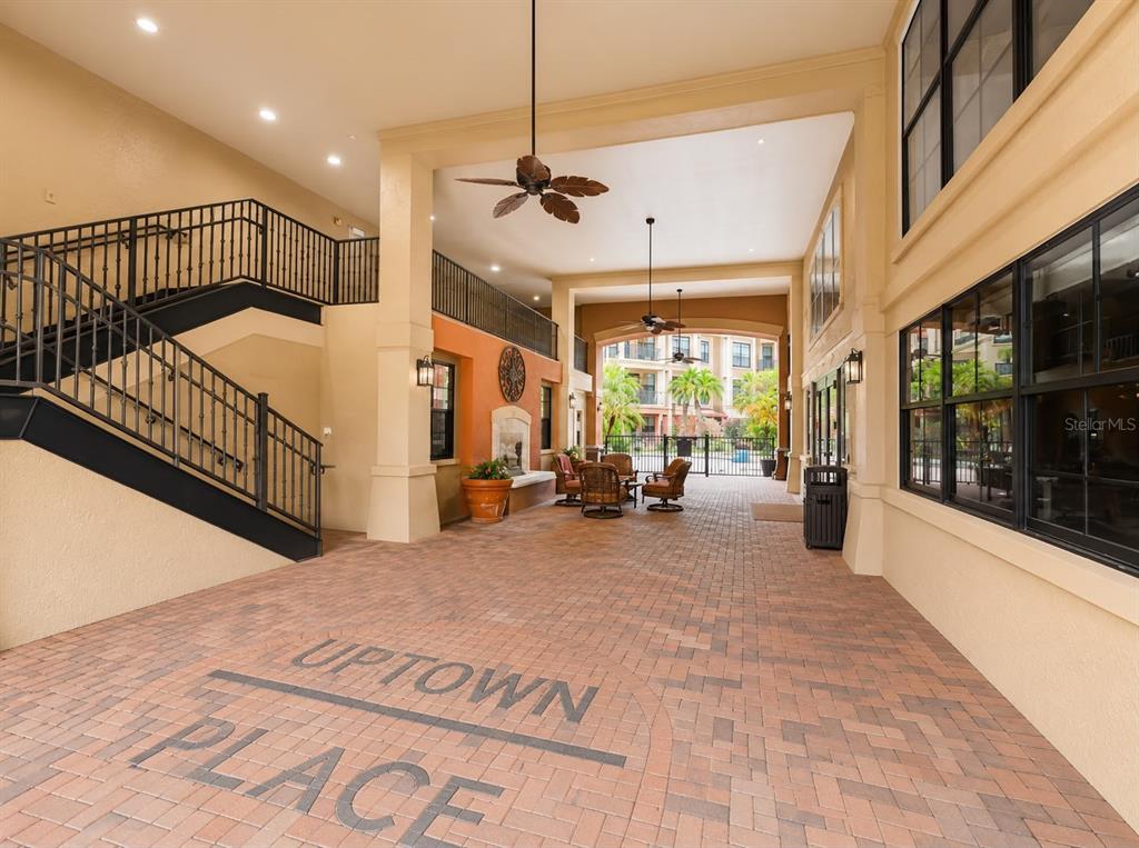 An outdoor covered patio features brick flooring, a staircase, and seating near a fireplace — 911 N ORANGE AVENUE UNIT 115, ORLANDO, FL
