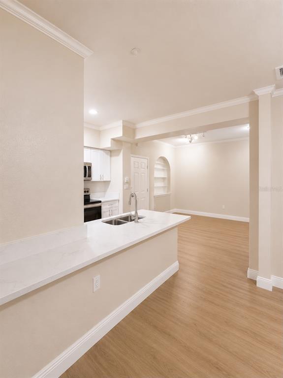 A kitchen with a white quartz breakfast bar overlooks an open living area with flooring — 911 N ORANGE AVENUE UNIT 115, ORLANDO, FL