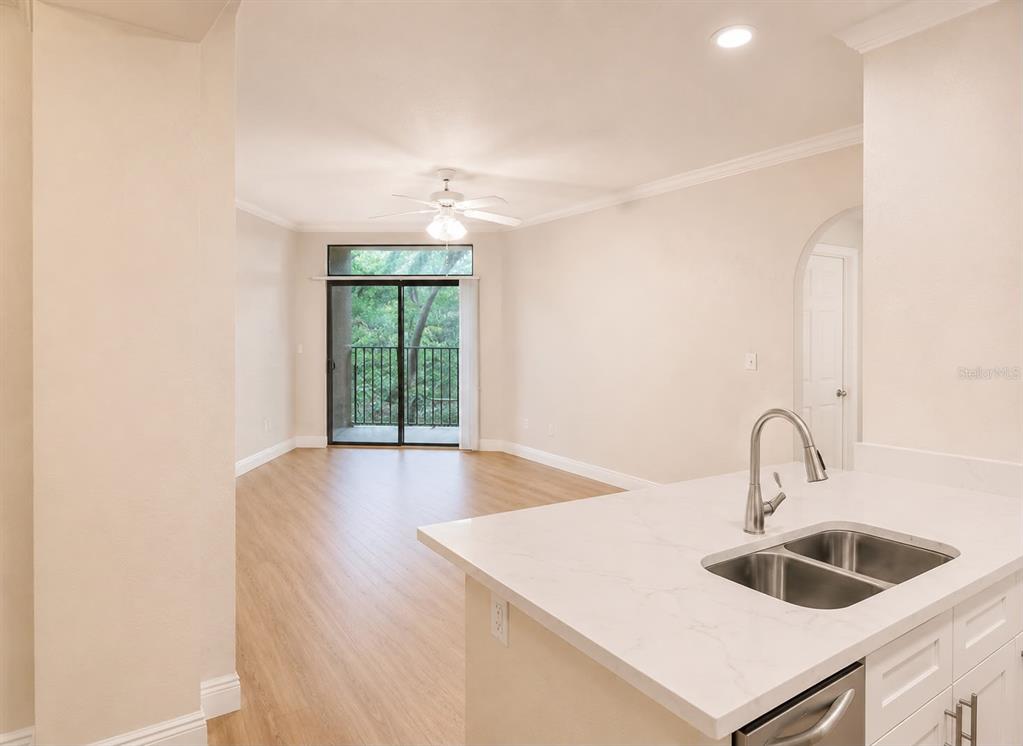 A kitchen island with a double sink overlooks an open living area with a balcony — 911 N ORANGE AVENUE UNIT 115, ORLANDO, FL