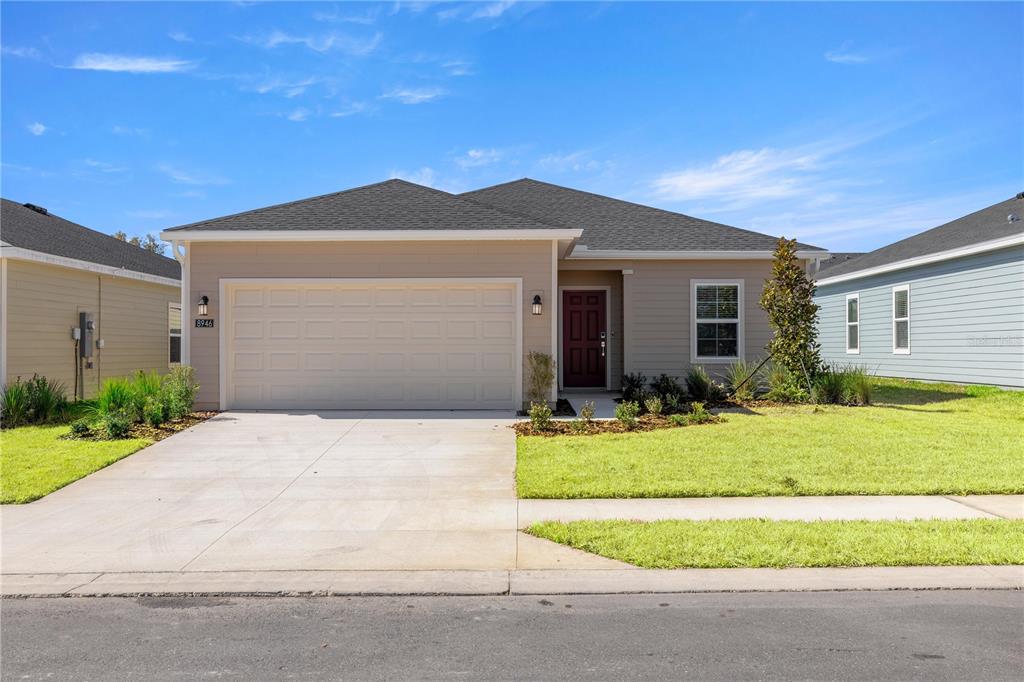 A single-story house with beige siding, a two-car garage, and a dark red front door — 3578 NE 38TH LANE, OCALA, FL
