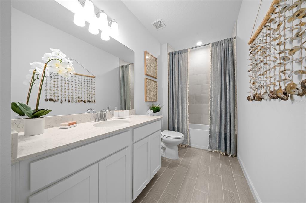 A bright bathroom features a white vanity, a tub-shower combo, and coastal-themed wall decor — 3578 NE 38TH LANE, OCALA, FL