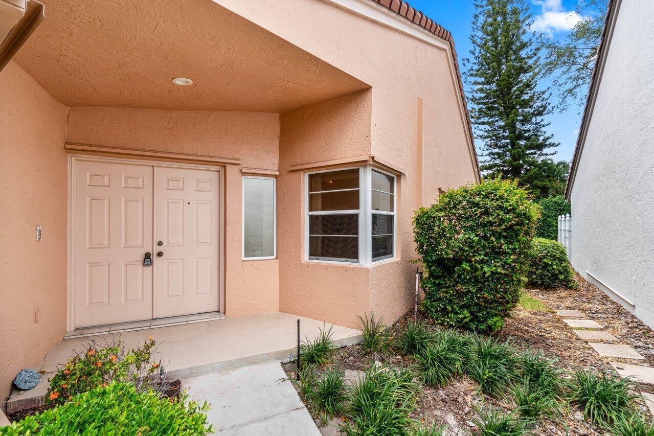A peach-colored house exterior features a double front door, a bay window, and landscaping — 10001 Country Brook Road, Boca Raton FL 33428, BOCA RATON, FL