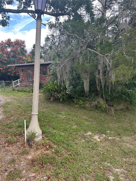 A brick house is partially obscured by trees and Spanish moss behind a lamp post — 4998 LAKE LOWERY ROAD, HAINES CITY, FL