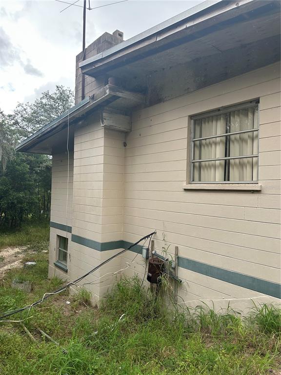 The exterior side of a beige concrete block house features a chimney and exposed wiring — 4998 LAKE LOWERY ROAD, HAINES CITY, FL
