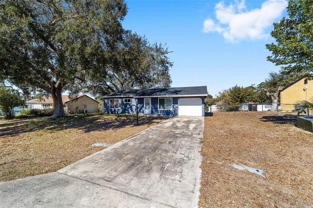 A blue single-story house with a white garage door and a concrete driveway — 6 HICKORY TRACK PASS, OCALA, FL
