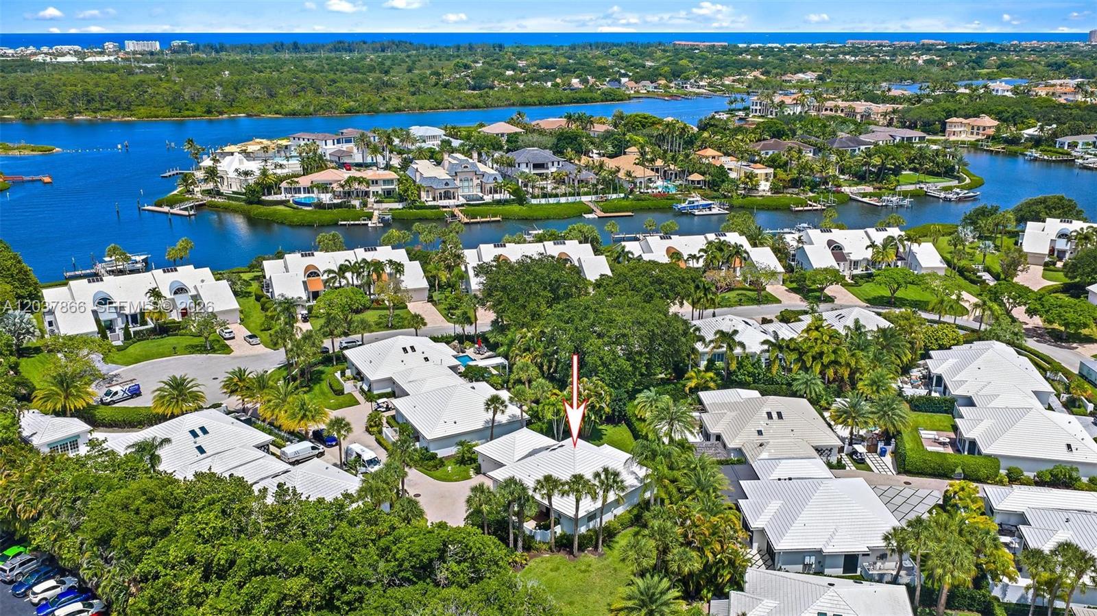 An aerial view shows a residential neighborhood with white-roofed houses surrounded by lush green trees — 4501 Captains Way, Jupiter FL 33477, JUPITER, FL