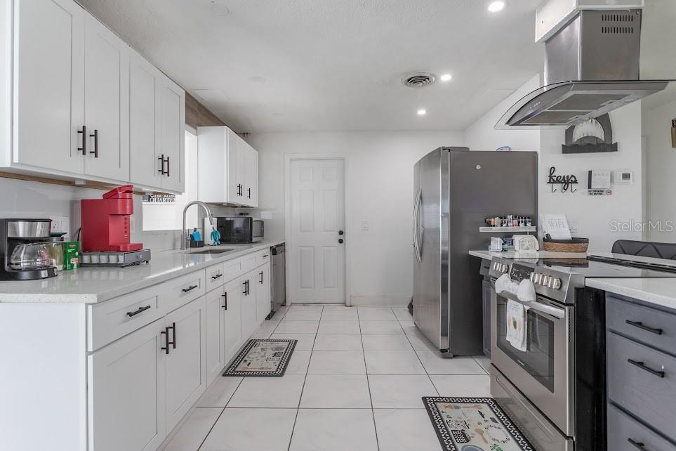 A modern kitchen features white cabinetry, stainless steel appliances, and light-colored tile flooring — 225 RICHLAND, MERRITT ISLAND, FL