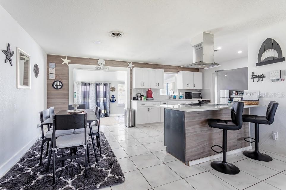 A kitchen and dining area with white cabinets, a wood-paneled wall, and a center island — 225 RICHLAND, MERRITT ISLAND, FL