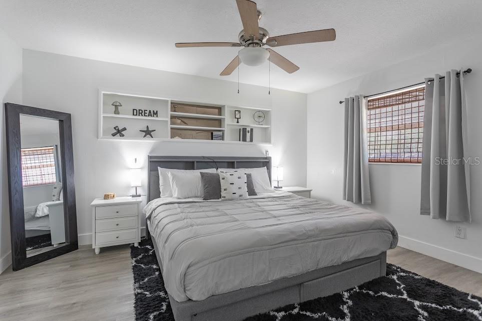 A bedroom features a gray upholstered bed, white built-in shelving, and a large floor mirror — 225 RICHLAND, MERRITT ISLAND, FL