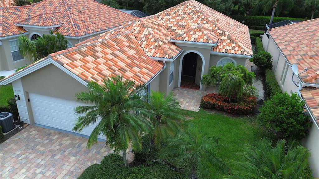 An aerial view of a suburban house with a tiled roof and a paved driveway — 4402 NOVATO COURT, NAPLES, FL