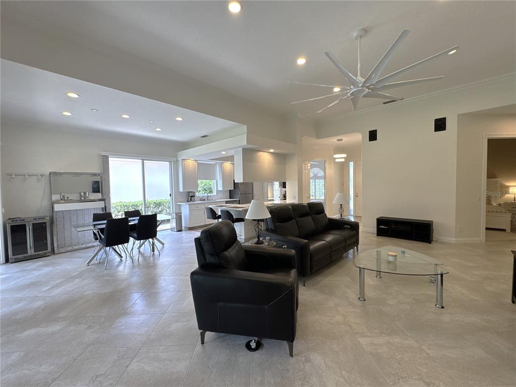 An open-concept living and dining area features tile flooring, a large ceiling fan, and furniture — 4402 NOVATO COURT, NAPLES, FL