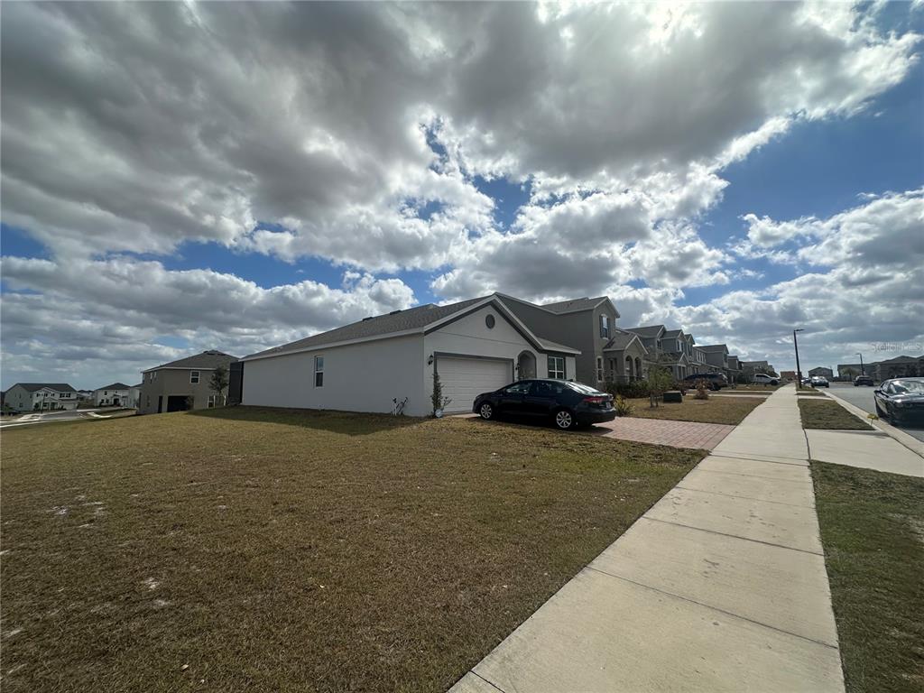 A single-story house with a white exterior and a two-car garage sits on a corner lot — 7776 MARSALA STREET, CLERMONT, FL