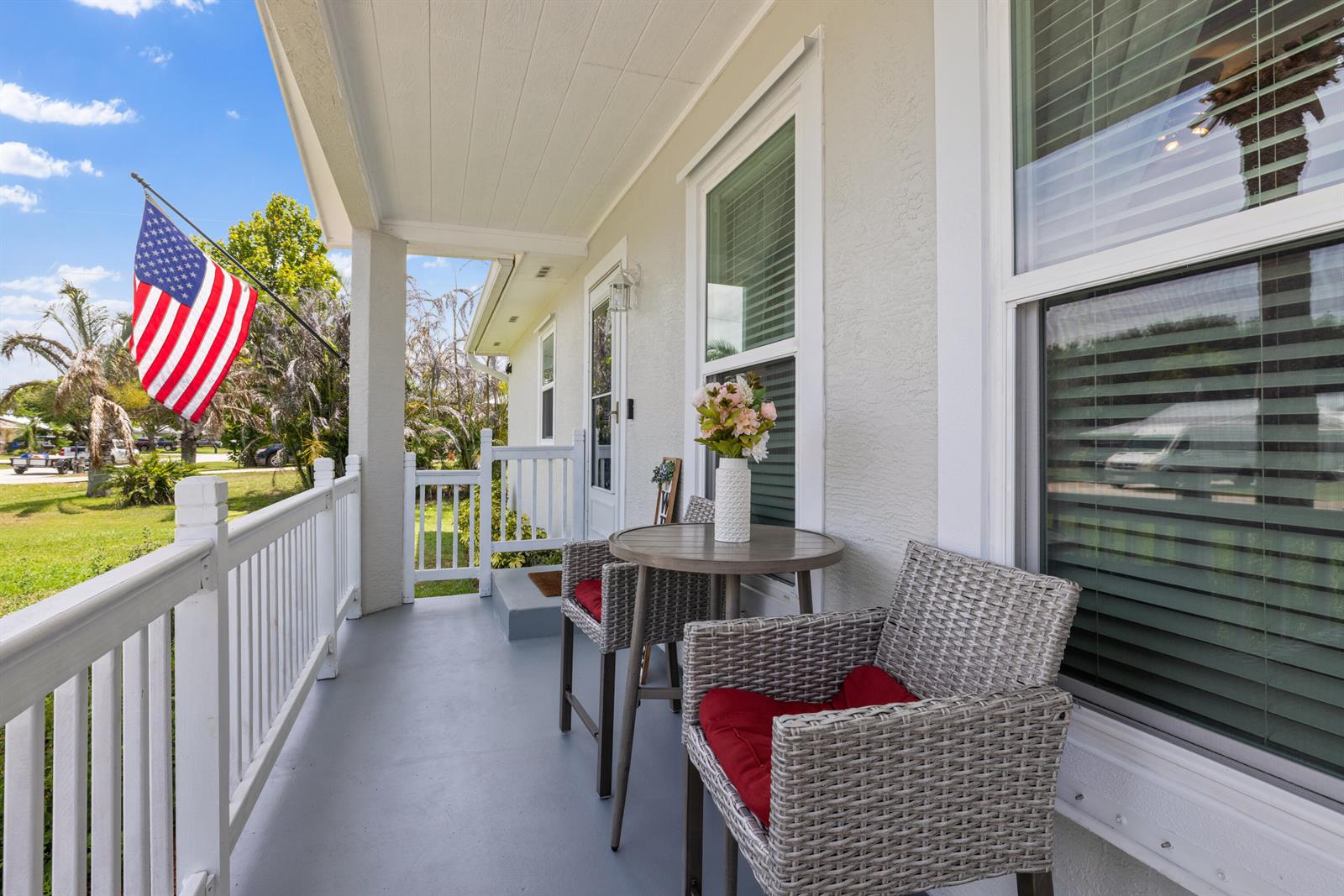 A covered front porch features gray flooring, white railings, and a small bistro set — 305 17th Avenue, Vero Beach FL 32962, VERO BEACH, FL