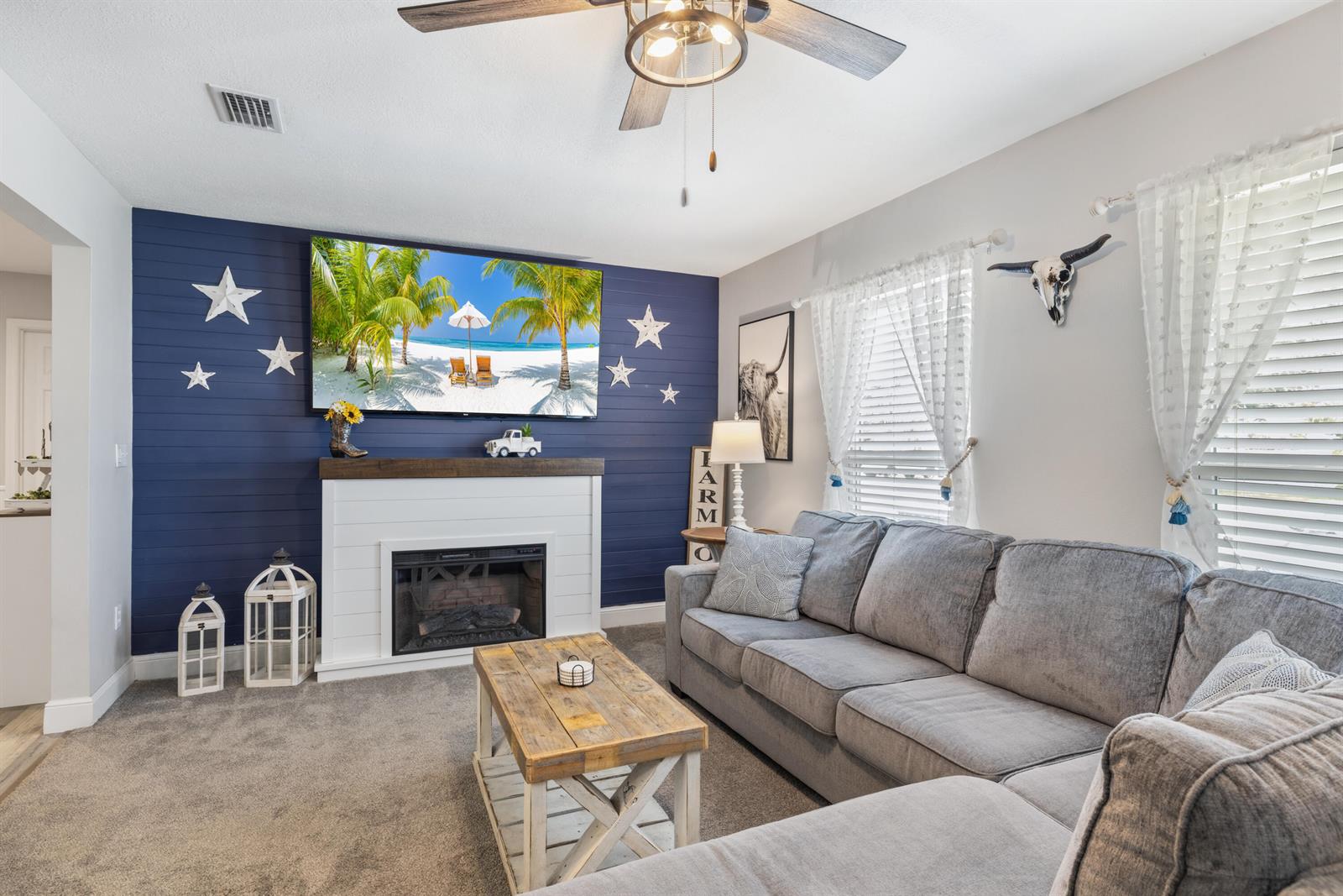 A living room features a blue shiplap accent wall with a fireplace and sectional sofa — 305 17th Avenue, Vero Beach FL 32962, VERO BEACH, FL