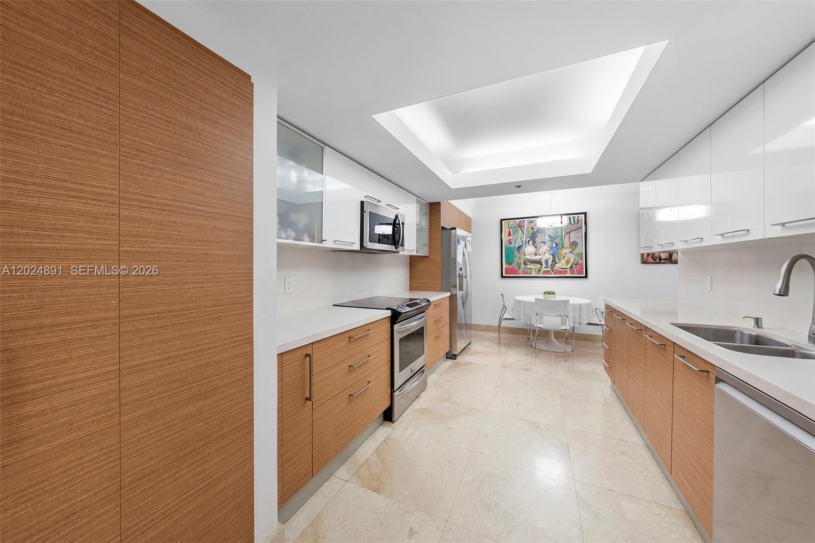 A modern galley kitchen features wood-grain and white cabinets with stainless steel appliances — 10175 Collins Ave # 1505, Bal Harbour FL 33154, BAL HARBOUR, FL